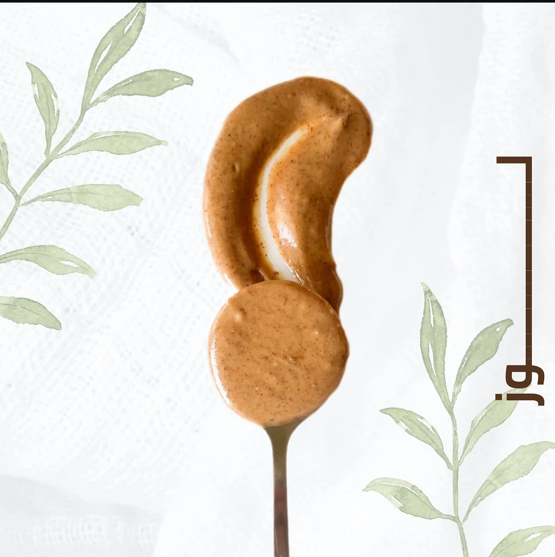 Almond butter on a spoon, framed by sage botanical illustrations.