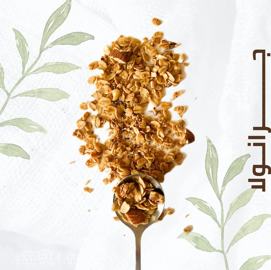 Granola and nuts arranged around a spoon with pale green illustrated leaves.